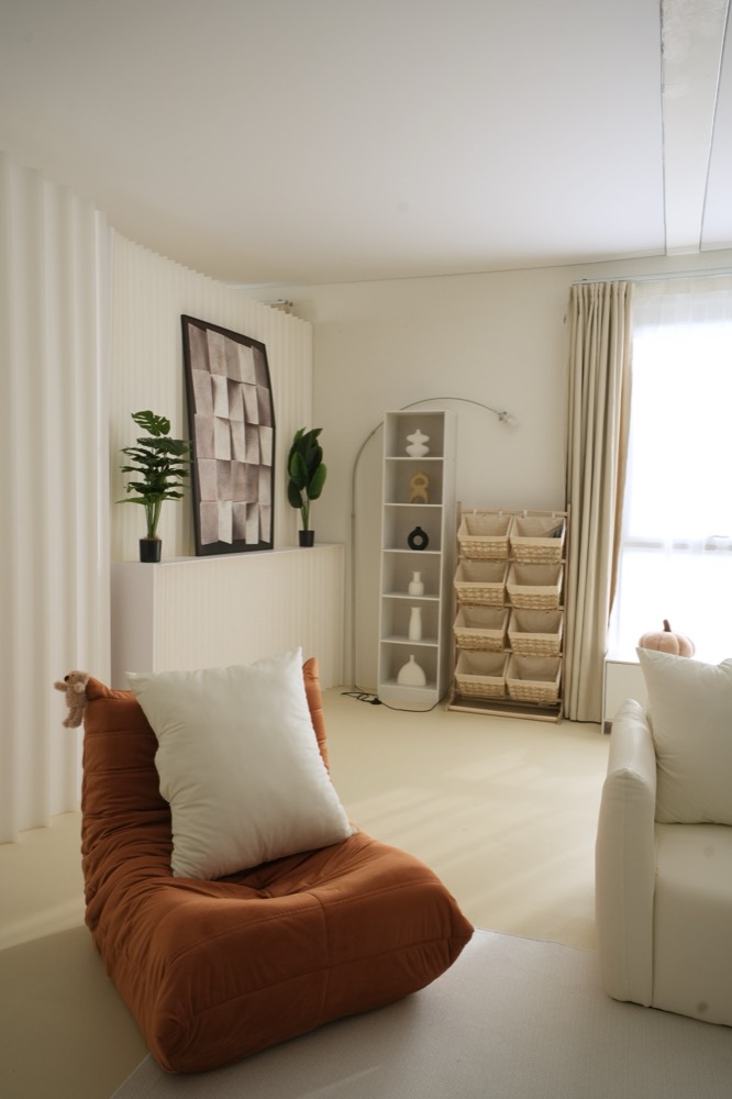 Burnt-orange lounge chair with a cream cushion beside the window