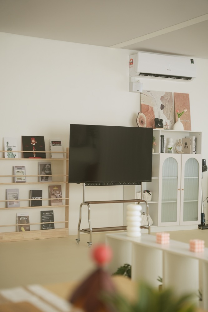 TV on a rolling stand beside a magazine rack and arched cabinet